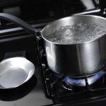 Water,Boiling,In,A,Stainless,Steal,Pot,On,A,Black